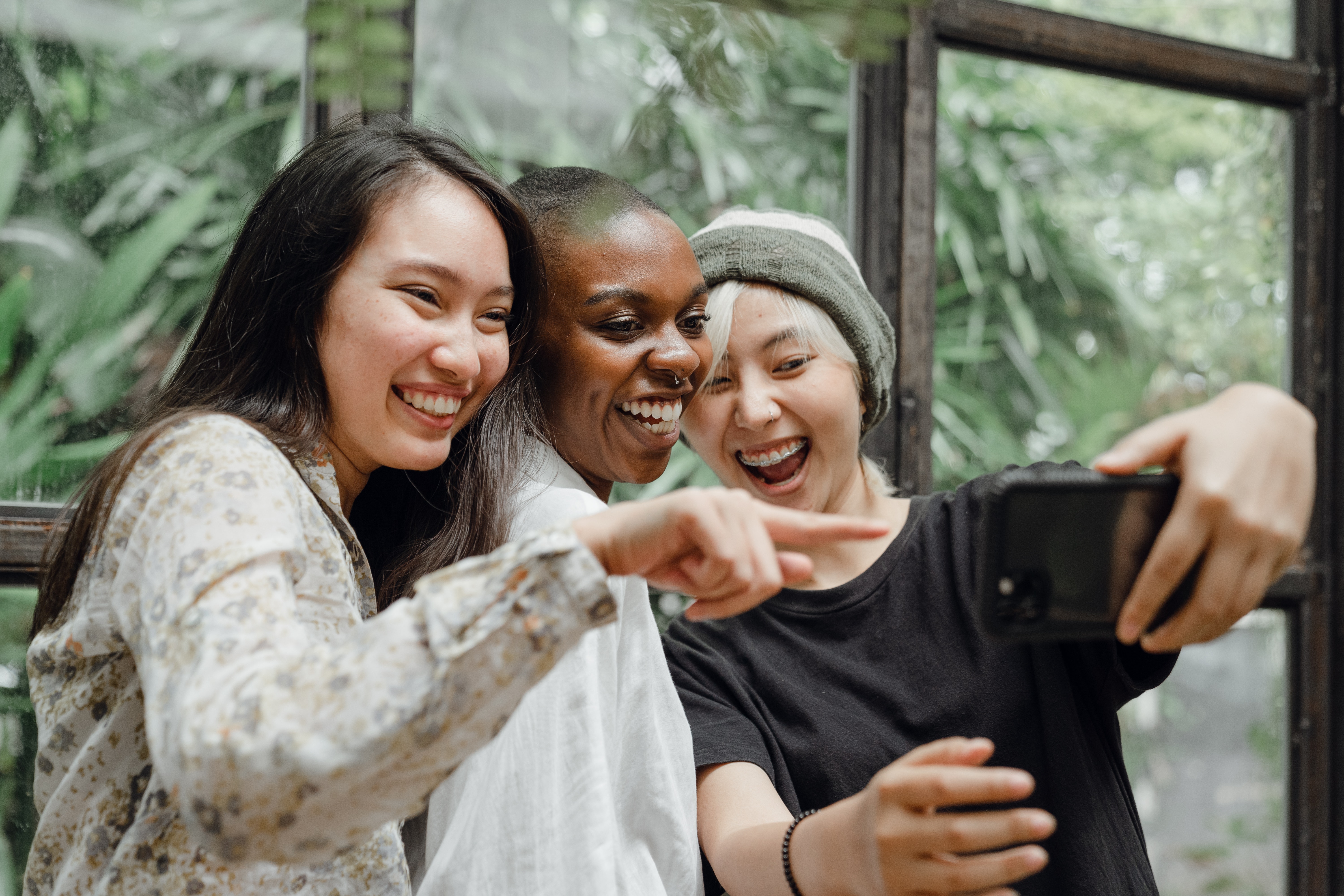 Image Description: Three laughing women looking at a mobile phone.