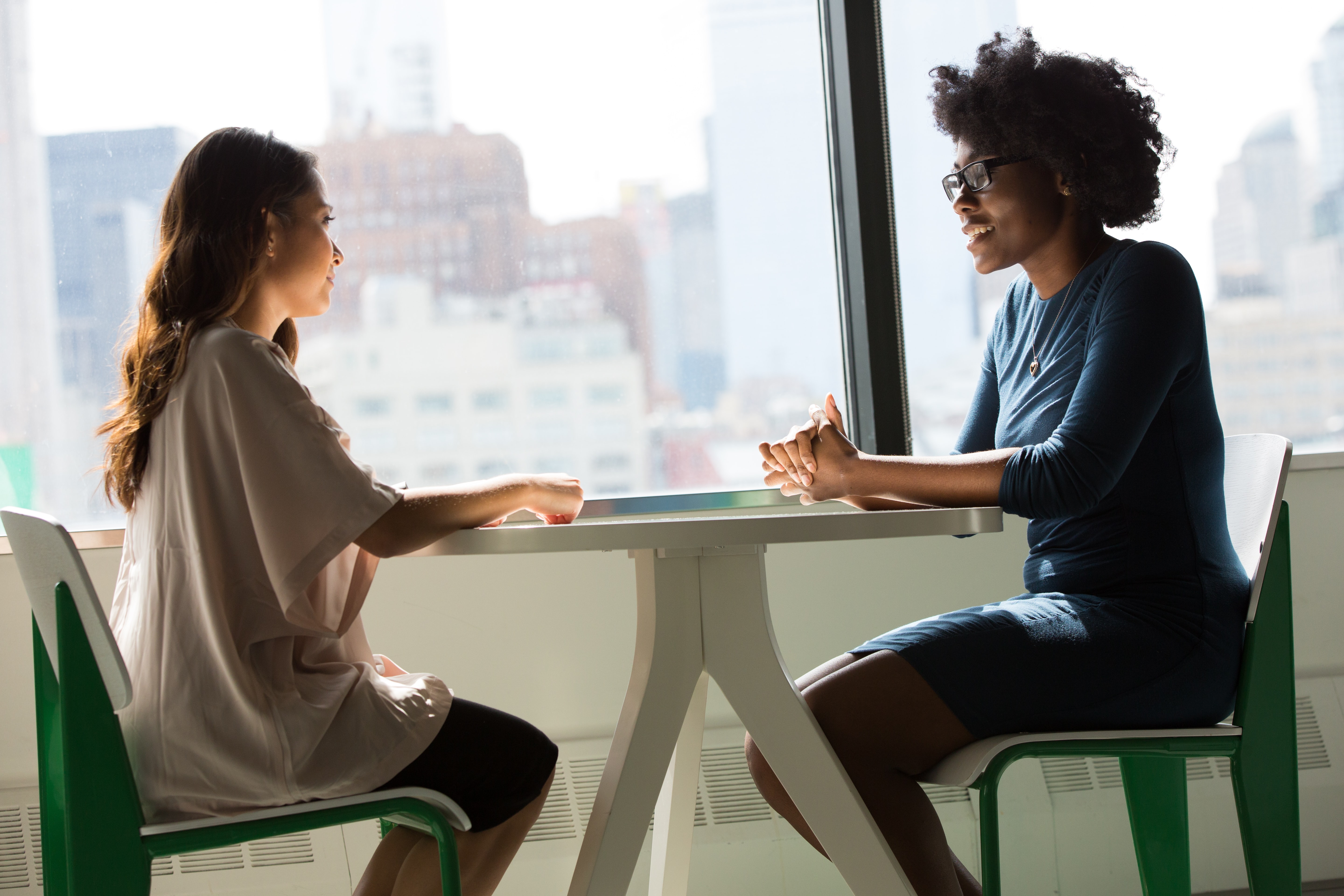 A black woman and a white woman sitting around a table chatting. Photo by Christina @ wocintechchat.com on Unsplash