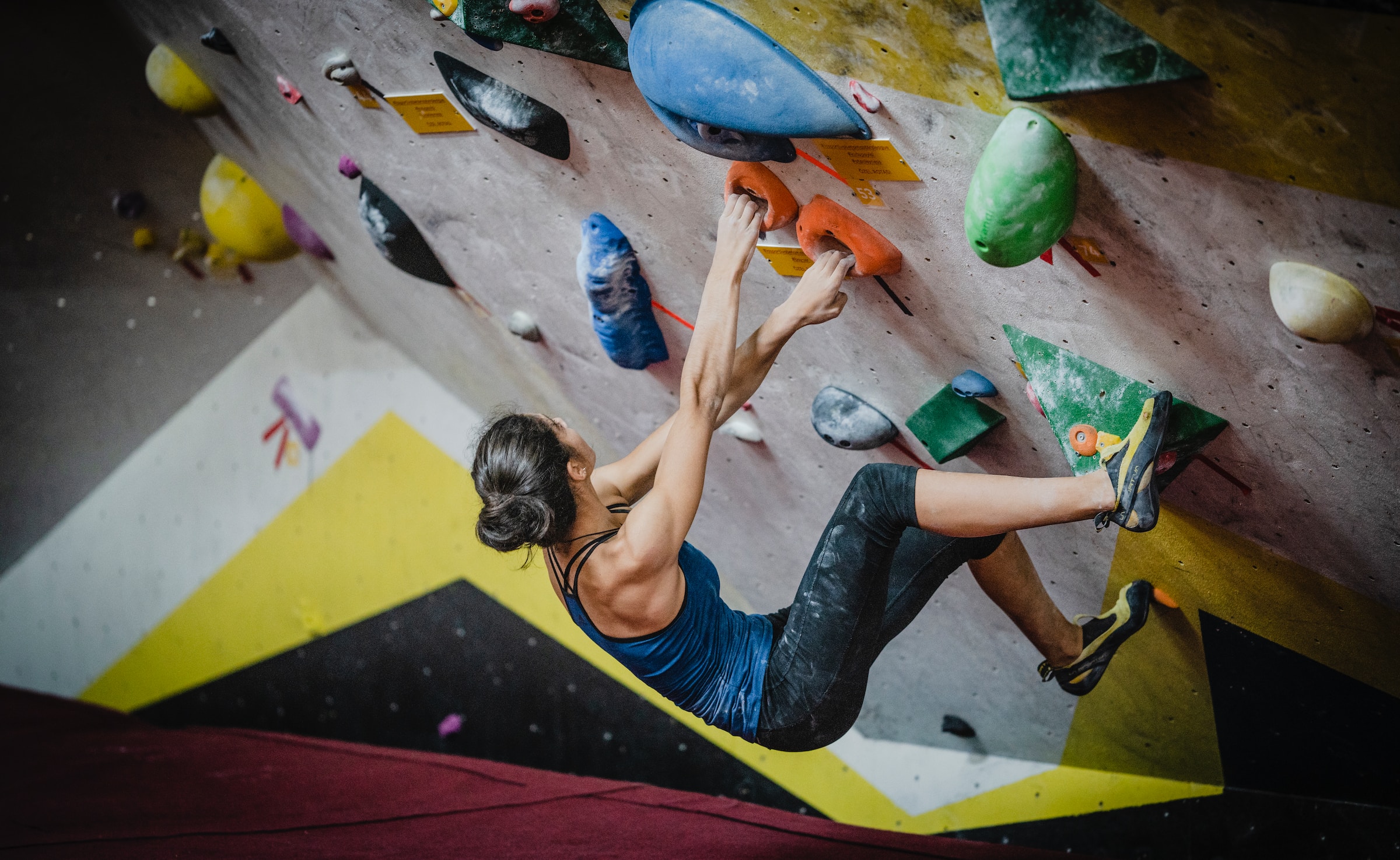 a woman climbing an indoor climbing wall