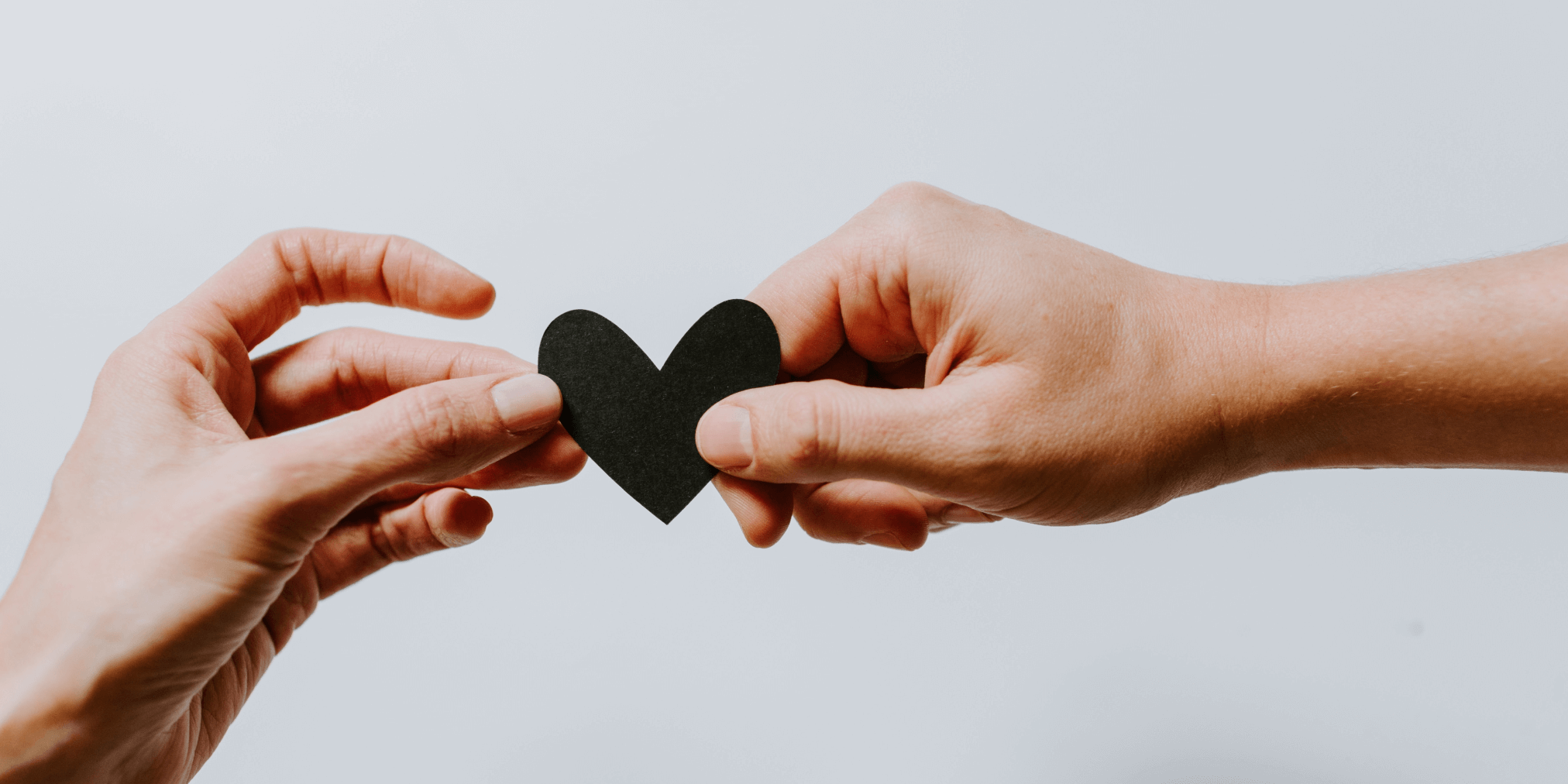 two hands holding a paper heart