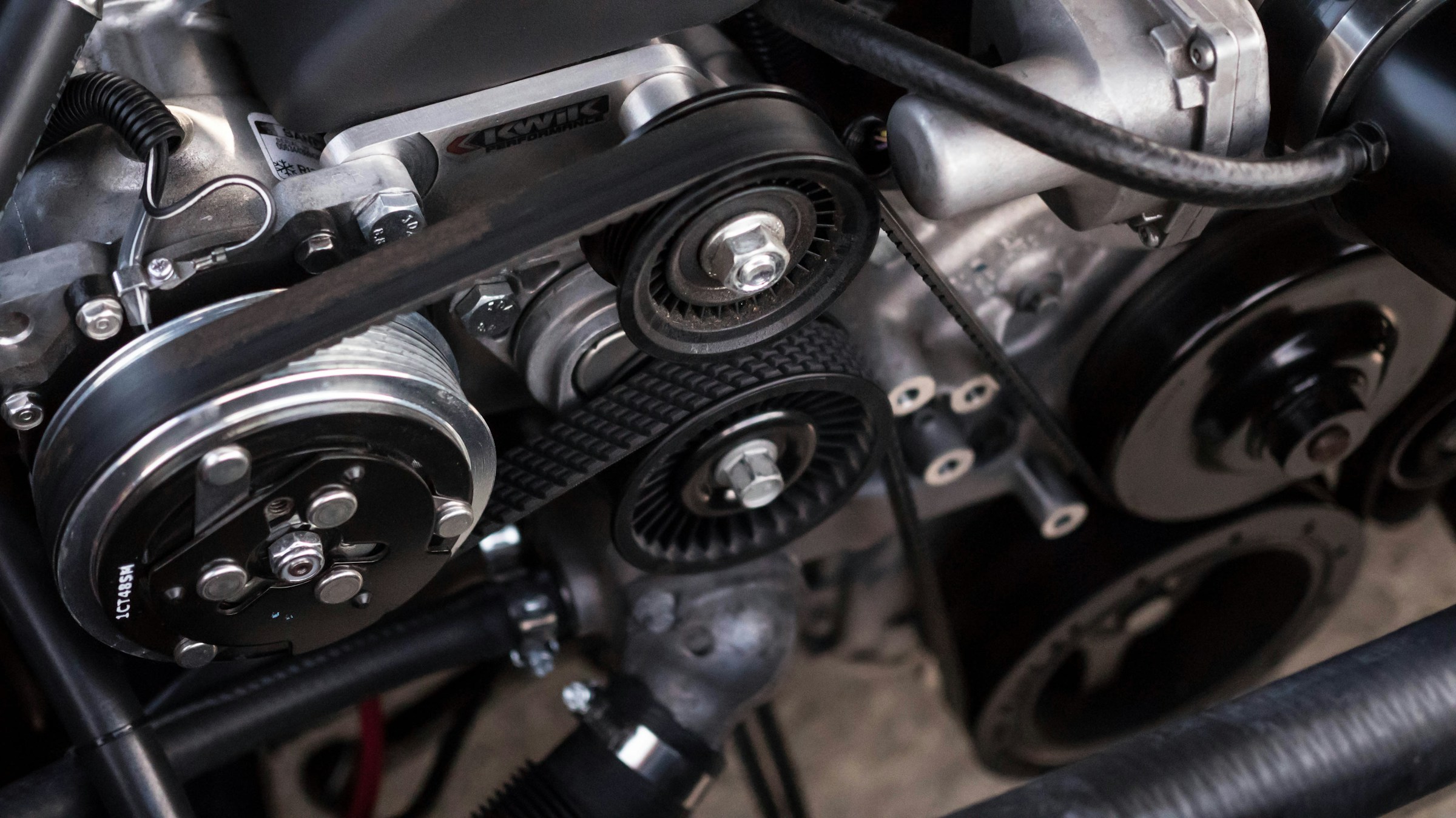 Photograph of an engine, focused on the belt and pulleys